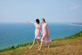 Two women wearing pink dresses walking on the grass